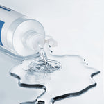 Toerning bottle pouring clear liquid onto a glossy droplet splash shape