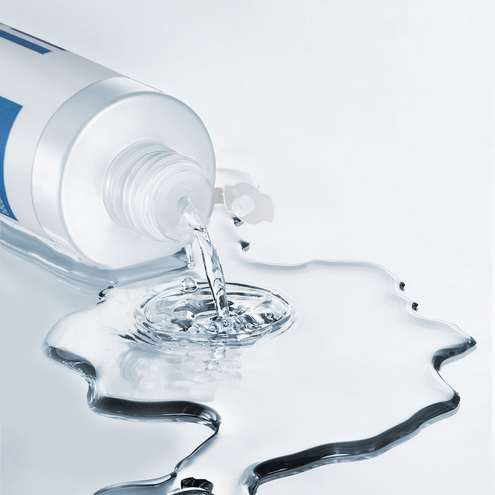 Toerning bottle pouring clear liquid onto a glossy droplet splash shape