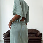 Women's green maxi dress back view with fitted waist, draped sleeves, and asymmetrical cut