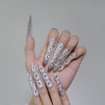 Hand wearing long almond silver rhinestone press-on nails with 3D crystal detailing
