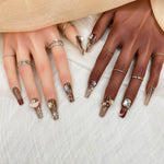 Short press-on nail set featuring brown and nude glossy nails with rhinestones and rose details