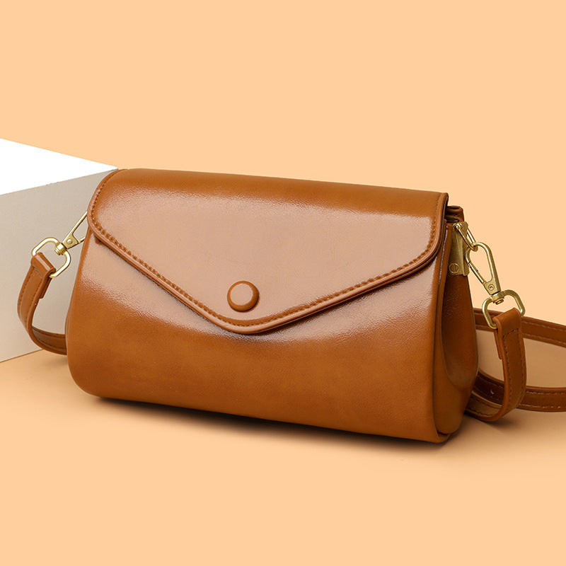Light brown PU crossbody bag with flap front, circular snap, and gold-tone hardware