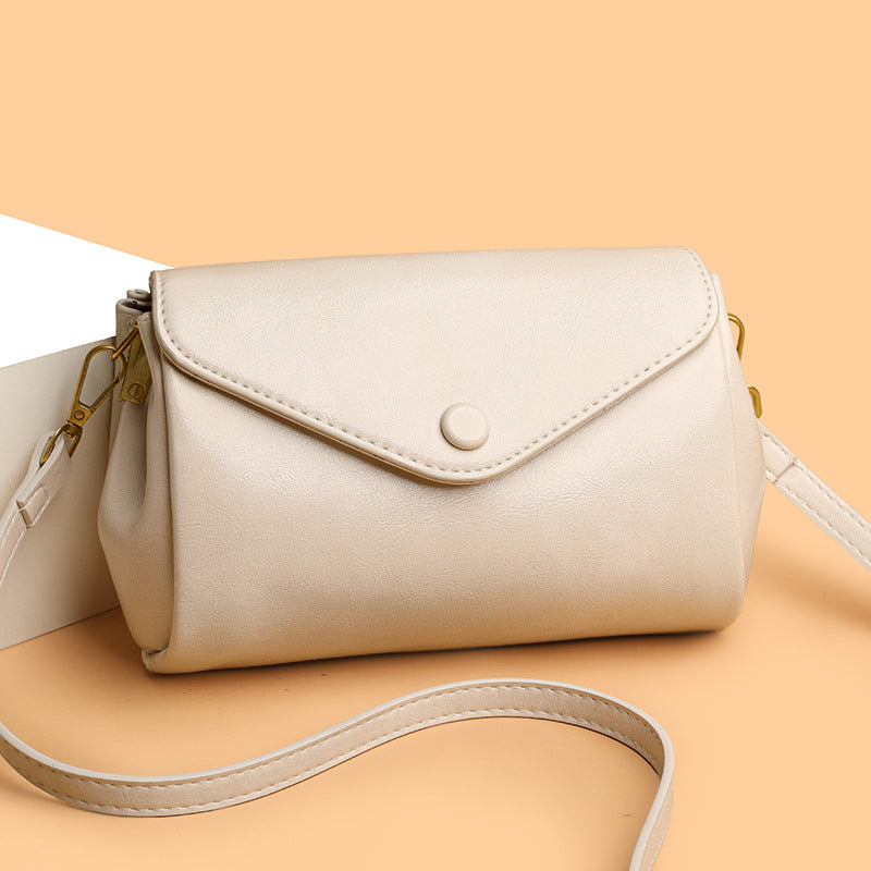 Beige-white PU crossbody bag with flap front, circular snap, and crossbody strap