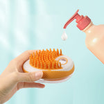 Pet bath brush with orange bristle side and shower gel dispenser dropping onto pads