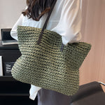 Woven shoulder beach bag in olive green with black top handles and shoulder strap