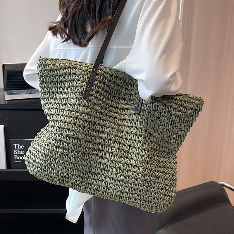 Woven shoulder beach bag in olive green with black top handles and shoulder strap