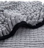 Close-up of gray microfiber bath towel with shaggy loop pile and black-edged seam