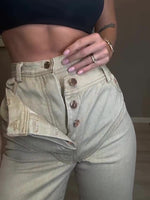 Light green high-waist denim jeans close-up, buttoned waistband and front pockets