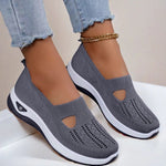 Dark gray mesh slip-on flat shoes with oval cutouts and white cushioned soles