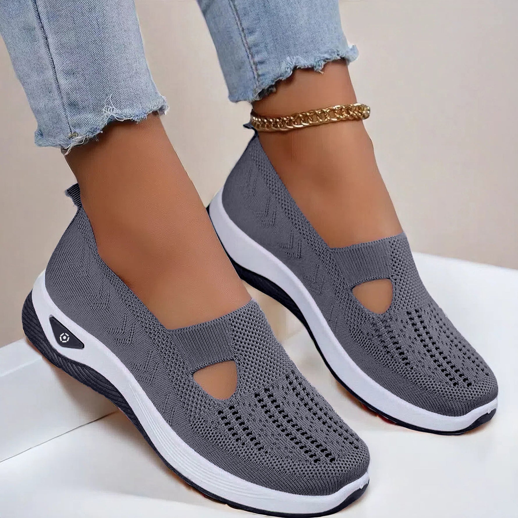 Dark gray mesh slip-on flat shoes with oval cutouts and white cushioned soles