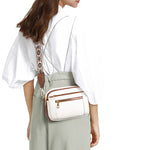 White crossbody bag with floral embroidered strap and dual front zippers, worn crossbody