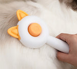Self-cleaning pet brush with orange button and cat-ear head being pulled through fur