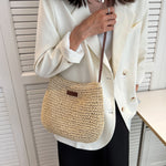 Woven straw shoulder tote with dark brown trim and short strap, worn with white blazer
