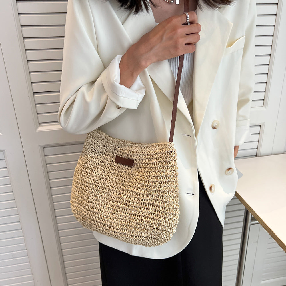 Woven straw shoulder tote with dark brown trim and short strap, worn with white blazer