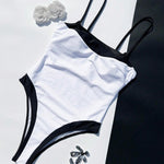 Color-block one-piece swimsuit detail: black-trim V-neck, white body, open-back straps