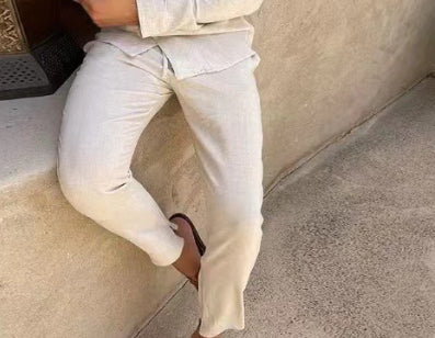 White slim trousers with shirt hem tucked in, long sleeves and lapel neckline visible.