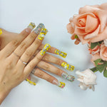 Hand wearing duck-themed yellow rhinestone nails in medium square shape