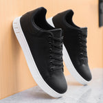 Black lace-up flat casual shoes with round toe, black laces, and white textured sole